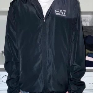 Emporio Armani Windbreaker - Snygg svart vindjacka från Emporio Armani perfekt nu för våren. Riktigt bra skick, inga defekter. Nypris ligger på ca 1000 mitt pris 650. Pris kan diskuteras vid snabb affär!