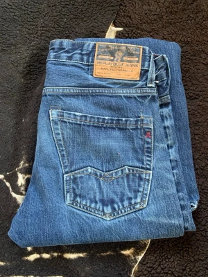 Blå jeans från Replay - Ett par klassiska blå jeans från Replay med raka ben och snygga slitningar. Jeansen har fem fickor, tydliga sömmar och en läderpatch med Replay-logga bak i midjan. Perfekta för dig som gillar en tidlös och avslappnad stil. W31 L34, Skriv vid funderingar! Svarar snabbt.