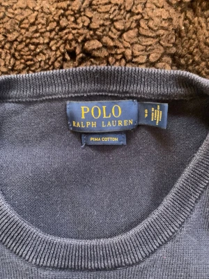 Mörkblå tröja från Polo Ralph Lauren - Snygg mörkblå tröja från Polo Ralph Lauren i mjuk Pima Cotton. Diskret broderad logga på bröstet. Långa ärmar och ribbade muddar vid ärmslut och nederkant. Skriv vid funderingar! Svarar snabbt.