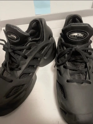 Czarne buty adidas, Svarta Adidas Climacool sneakers - Unika svarta Adidas Climacool sneakers med futuristisk design och ventilerande meshpaneler. Skorna har snörning, robust sula och coola utskärningar på sidorna för extra ventilation. Perfekta för dig som vill sticka ut med en sportig och modern look.