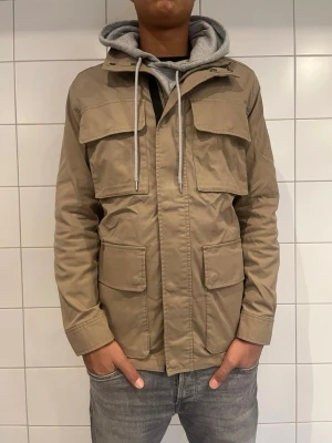 Safarijacka  - Hej! Säljer denna rikigt stiliga jacka med en fin färg perfekt nu till våren, modellen är 188 cm lång och den sitter lite pösigt på honom backifrån! Skriv gärna vid intresse eller funderingar. Helt ny! 