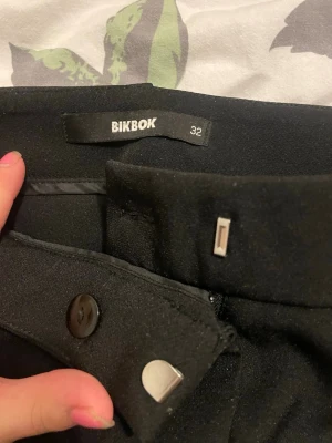Svarta kostymbyxor från BikBok - Snygga svarta kostymbyxor från BikBok med klassisk rak passform och lågmidjade, dem är använda cirka 4 gånger och är lite glittriga. Original pris är 499kr och jag vill inte gå ner i pris. Skriv om du har frågor eller nåt!