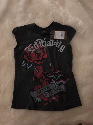 Svart Ed Hardy topp med tryck - Cool svart topp från Ed Hardy. Helt ny med prislapp, säljer då jag köpte fel storlek. Köptes för ca 600kr