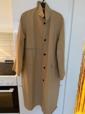 Beige trenchcoat SuperDry/Cult Studio - Lång Trenchcoat från Superdry/Cult Studio, helt ny med prislappen kvar. Nypris 2.500kr 