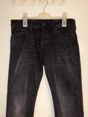 Svarta slim jeans - Säljer ett par svarta jeans från Jack and Jones med slim passform som knappt är använda. Jeansen har en lätt tvättad look och är tillverkade i ett mjukt denimtyg. Perfekta för en avslappnad och stilren outfit. Storlek: W30 L32 Modell: Slim/Glenn 