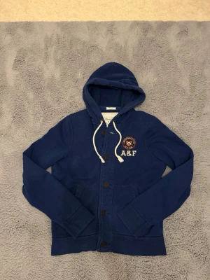 Blå cardigan från Abercrombie & Fitch - Sjukt eftertraktad Abercrombie & Fitch cardigan i blå – stl L. Stilren och populär modell som är svår att få tag på i denna färg och storlek. Blå färg som är lätt att matcha och alltid funkar. • Storlek: L • Skick: Väldigt bra • Färg: Blå • Original & hög kvalitet Varför den är eftertraktad: – Populär Abercrombie & Fitch-modell – Snygg och lättmatchad blå färg – Svår att hitta i fint skick – Säljs snabbt när de dyker upp Skriv vid intresse eller för snabb affär✌️ Skickas inom 24h 📦 