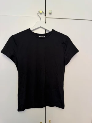 Svart basic t-shirt från H&M - En svart basic t-shirt från H&M med rund hals och korta ärmar. Perfekt att matcha med jeans eller shorts för en clean och enkel look. Har som ett träningsmaterial