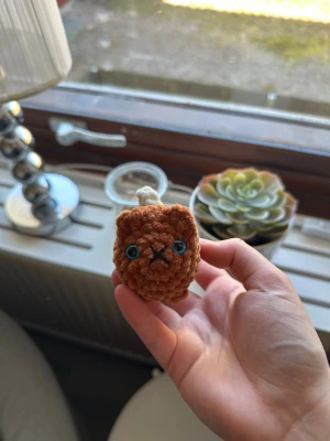 Virkad liten katt med beige svans - Söt liten virkad orange/brun katt med beige svans och blå ögon. Ca 8 cm lång (svans inkluderad). Katten har säkerhetsögon som inte är lämpliga för barn under 3 år💗