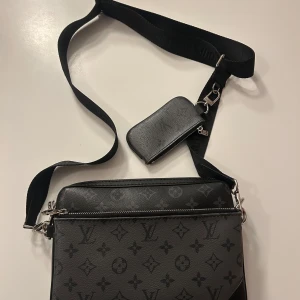 Lv trio bag - Snygg svart axelväska från Louis Vuitton som man kan ta isär till 3 olika små väskor. Den är köpt 2020 och har inte använda den dess. Den är använd fåtal gånger. Den lilla delen som ser ut som en plånbok är borta. 