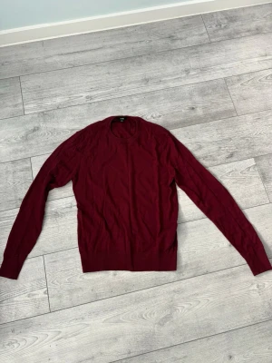 Vinröd stickad tröja - Vinröd stickad tröja ifrån Uniqlo med rund halsringning och långa ärmar. Tröjan har en enkel och stilren design med ribbade muddar vid ärmslut och nederkant. Perfekt att matcha med jeans eller kjol för en avslappnad look.                       Jag är 176cm och den är lite kort på mig i längden 