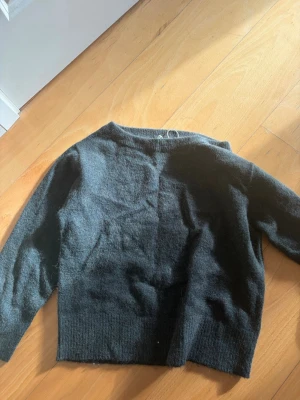 Mörkgrön stickad tröja Gina Tricot - Mysig mörkgrön stickad tröja från Gina Tricot. Tröjan har en enkel, rak passform med långa ärmar och ribbstickade muddar. Perfekt för kalla dagar och lätt att matcha med olika outfits.