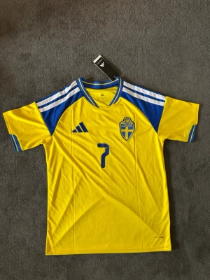 Sverige VM 26/27 hemma Bergvall 7 - Fotbollströja med Bergvall på ryggen. Tröjan är helt ny med tagg kvar och i perfekt skick. Perfekt för dig som är supporter, samlar på fotbollströjor eller vill ha en snygg tröja till träning och vardag.                                                                      🟡 Skickas inom 24 timmar.                                         Vid intresse eller frågor är det bara att skicka 👍