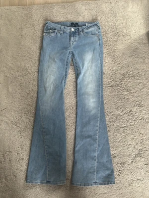True Religion Joey flare jeans ljusblå - Säljer ett par ljusblå True Religion Joey jeans med låg midja och utsvängda ben. Klassisk femficksmodell med slitningar framtill för en cool vintagekänsla. Pris kan diskuteras!