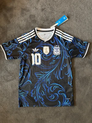 Argentina VM 26/27 borta Messi 10 - Fotbollströja med Messi på ryggen. Tröjan är helt ny med tagg kvar och i perfekt skick. Perfekt för dig som är supporter, samlar på fotbollströjor eller vill ha en snygg tröja till träning och vardag.                                                                      ▪️ Skickas inom 24 timmar.                                         Vid intresse eller frågor är det bara att skicka 👍