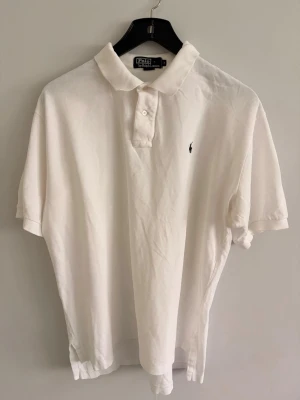 Polo Ralph Lauren piké  - • 🇸🇪 Vit blå Piké från Polo Ralph Lauren. Broderad logga på bröstet.   Använd, men fortfarande i fräscht skick utan några speciella anmärkningar.   Pris går alltid att diskutera vid snabb affär 🥂