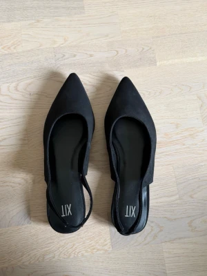 Ballerinaskor  - Svarta ballerinaskor med spetsig tå och öppen häl. Köpta från DinSko. Aldrig använda, endast provat hemma. Säljer på grund av kommer inte till användning 
