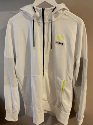  Nike Air Max zip hoodie-Ny skick - Vit modell med svarta detaljer och neon-gula Air Max-loggor som ger en sportig och modern look. Tillverkad i skönt funktionsmaterial med huva och dragkedja framtill.