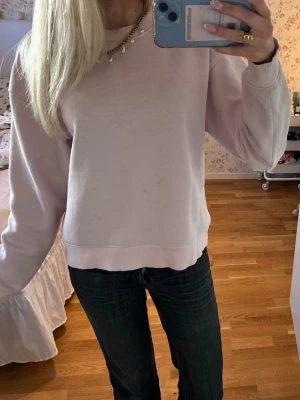 Ljusrosa sweatshirt från Gina Tricot - En ljusrosa sweatshirt från Gina Tricot, basically basics-kollektionen. Tröjan har rund halsringning, ribbade muddar vid ärmslut och nederkant samt en avslappnad passform. Perfekt för en enkel och stilren look.