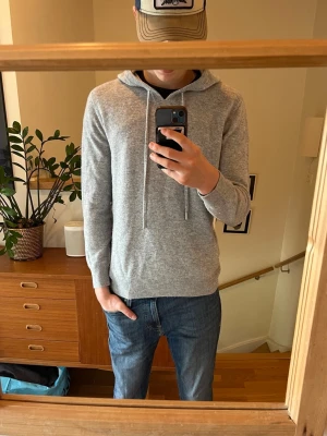 Grå Kashmir hoodie - Denna gråa Kashmir hoodie är riktigt fet och trendig. Den är kvalitativ och väldigt stilren i designen!