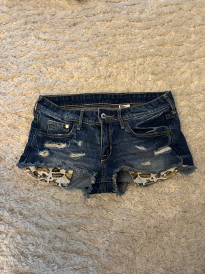 Blå slitna denimshorts med leoparddetalj - Jätte fina jeans shorts, dom är i bra skick och pris kan diskuteras