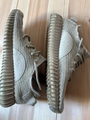 Beige Yeezy Boost 350 sneakers - Säljer ett par Yeezy Boost 350 sneakers i beige färg med stickad ovandel och matchande snören. Skorna har en chunky, räfflad sula i gummi och en låg silhuett. Perfekta för dig som gillar streetwear och vill ha något som sticker ut.