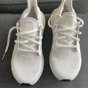 Vita Adidas Ultraboost sneakers. Storlek 42 och 43 - Snygga vita Adidas Ultraboost sneakers med stickad ovandel och klassisk snörning. Skorna har en bekväm och responsiv sula samt diskret Adidas-logga på plösen. Perfekta för dig som gillar stilrena och sportiga vibes. Finns storlek 42 och 43