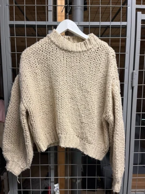 Beige chunky stickad tröja - Säljer en beige chunky stickad tröja med hög krage och breda ärmar. Tröjan har en croppad passform och grovstickat mönster som ger en riktigt cozy vibe. 