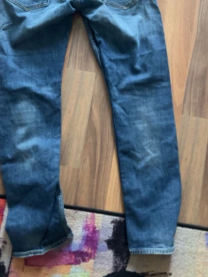 Replay jeans - Säljer ett par blå jeans med rak passform och klassisk tvätt. Jeansen har fem fickor och subtila slitningar på framsidan. Materialet är denim och färgen är en mellanmörk blå nyans. Perfekt för dig som gillar en enkel och tidlös stil.