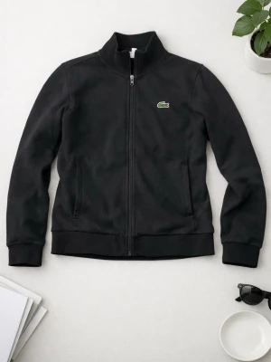 Svart zip hoodie från Lacoste - Säljer en svart Lacoste‑zip i fint skick. Klassisk modell med krokodilen på bröstet. Krokodilen höll på att lossna lite, så jag sydde fast den försiktigt – sitter stabilt nu och syns knappt. • Storlek M • Inga fläckar eller hål • Fräsch och ren • Passar både tjejer och killar • Använd fåtal gånger