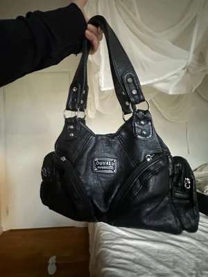 Svart axelväska  - Säljer denna supersnygga svarta handväska i läderimitation med silvriga detaljer och flera fack. Rymlig och får plats med allt man behöver. Knappt använd och i mycket bra skick.