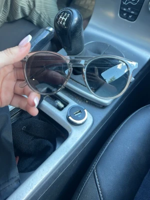 Bruna cat eye solglasögon - Snygga solglasögon i cat eye-modell med transparent brun båge och mörka glas. Perfekta för att lyfta din stil med en trendig touch. Lätta och bekväma att bära hela dagen.