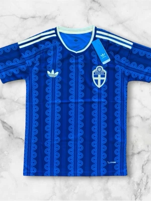 Blå Sverige tröja från Adidas - Säljer en blå kortärmad Sverige tröja från Adidas med retroinspirerat mönster och vita detaljer. Tröjan har Sveriges landslagsemblem på bröstet, klassiska Adidas-ränder på axlarna och vit ribbad krage. Perfekt för dig som vill sticka ut på match eller träning.
