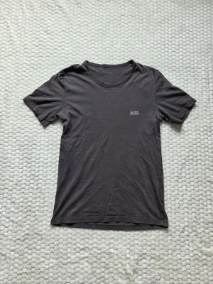 Hugo Boss T-shirt - Snygg mörkgrå t-shirt från Hugo Boss med diskret logga på bröstet. Klassisk rund halsringning och korta ärmar. Tillverkad i mjuk bomull som känns skön mot huden. Perfekt basplagg för en clean och stilren look. Priset kan självklart diskuteras!