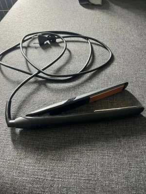 Svart plattång från Clas Ohlson - Säljer en svart plattång från Clas Ohlson med sladd och guldiga värmeplattor. Perfekt för att styla håret rakt eller skapa mjuka vågor. Enkel att använda och smidig att ta med sig tack vare sin kompakta form. Har använts, men fungerar som den ska!