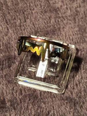 Regnbågsskimrande ring i metall - Cool ring i metall med regnbågsskimrande yta och ett unikt, vågigt mönster som går runt hela ringen. Ringen har en modern och edgy design som sticker ut och passar perfekt för dig som vill ha något annorlunda.