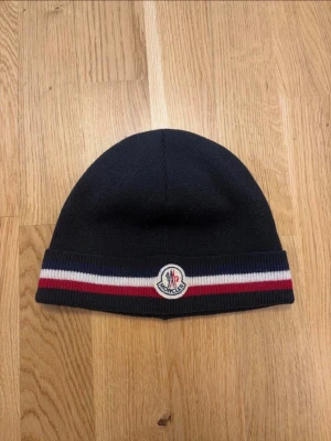 Moncler mössa - Moncler mössa i färgen marinblå storlek one-size skick 9,5/10. Äktehetsbevis finns på sista bilden. Hör av er för mer info ///