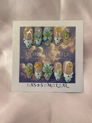 SeaBby (S);Medium Almond - Unika handgjorda press-on naglar i en medium lång mandelform. Designen har ljusblå och vita toner med handgjorda 3D-blommor, guldiga sjöhästar och sjöstjärnor samt prickar i vitt och blått. Storleken är S: 15 mm, 11,5 mm, 12 mm, 11 mm, 9 mm  och dekorationerna ger en lyxig och kreativ känsla.