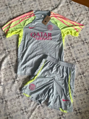 PSG träningsset grå/gul Nike - Psg fotbollsset i storlek M. Shortsen har fickor med dragkedjor. Helt nya och oanvända, perfekt till sommaren. Hör gärna av vid frågor!