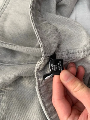 Ljusgrå raka jeans från booman  - Säljer ett par ljusgrå jeans från H&M med raka ben och klassisk femficksmodell. Jeansen har en avslappnad passform och är tillverkade i bomull. Perfekta för en chill och stilren look.