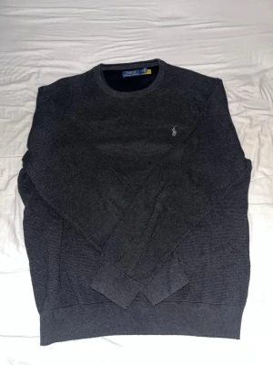 Mörkgrå/svart tröja från Polo Ralph Lauren - Mörkgrå/svart tunn stickad tröja från Polo Ralph Lauren. För stor för mig har ingen bild därför.