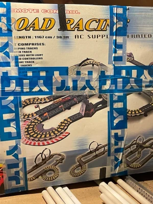 Remote Control Road Racing Bilsats - Säljer en Road Racing bilbana med fjärrkontroller och loopingbanor. Setet innehåller svarta och gula banbitar, två handkontroller och bilar. Perfekt för dig som gillar racing och vill ha en cool bana att köra på hemma.