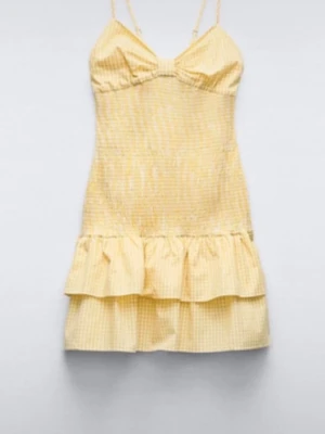 Populär Zara klänning - Perfekt till midsommar!! Supersöt gul och vit rutig kort klänning med smala axelband, volangkant och stor rosett i ryggen. Klänningen har en omlott-detalj bak och är perfekt för varma dagar. Tillverkad i lätt bomullsmaterial som känns luftigt och bekvämt.
