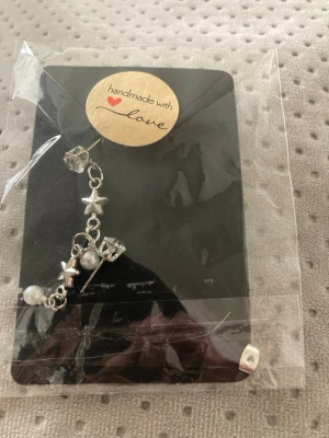 Handgjort örhänge med stjärnor och pärlor - Unikt handgjort örhänge i silverfärg med små stjärnberlocker, vita pärlor och klara kristalliknande detaljer. Perfekt för dig som gillar personliga accessoarer med lite extra bling och charm.