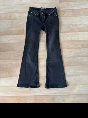 Svarta bootcut jeans från Crocker - Säljer ett par svarta bootcut jeans från lager 157  med klassisk femficksdesign och knappgylf. Jeansen har en lätt utsvängd passform och är tillverkade i denim med stretch för extra komfort. Perfekta för dig som gillar en retrostil.