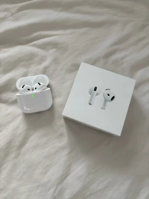 Apple AirPods med laddningsetui - Säljer ett par vita Apple AirPods med trådlöst laddningsetui. Snygg och stilren design i blank plast, perfekt för musik, poddar och samtal. Kommer med originalförpackning. Smidig touchkontroll och enkel anslutning till iPhone.
