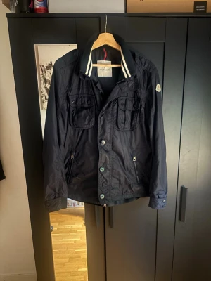 Moncler jacka  - Säljer denna svin snygga och unika jackan från moncler 💙. Jackan är i topp skick med endast minimala tecken på användning med tanken på att detta plagget går ej att få tag på längre! Skick: 8/10, jackan passar perfekt för de senare sommarkvällar där man vill sticka ut lite! Slå gärna en pling vid någon fundering 🙌