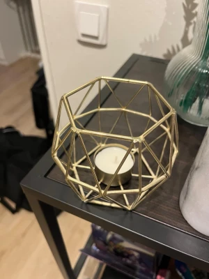 Guldig geometrisk ljuslykta i metall - Snygg ljuslykta i guldig metall med geometriskt mönster. Perfekt för värmeljus och ger ett modernt intryck till rummet. Passar bra som dekoration på bord eller hylla.