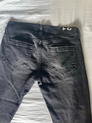 Svarta jeans från Dondup - Snygga svarta jeans från Dondup med klassisk femficksdesign och diskret D-detalj på bakfickan. Jeansen har en rak passform och är tillverkade i mjukt denimtyg med lätt tvättad look. Perfekt för dig som gillar stilrena och moderna jeans. Storleken är w31, för korta för mig.