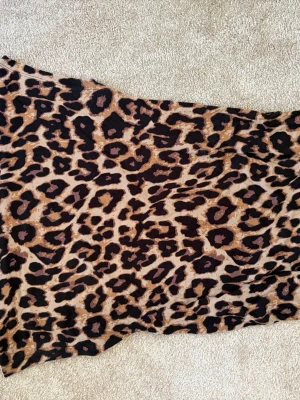 Leopardmönstrad topp Black Label - Säljer en leopardmönstrad topp från The Black Label Collection lager 157. Toppen har beige och bruna toner med svarta leopardfläckar. Materialet känns mjukt och stretchigt, troligen bomull eller polyester. Perfekt för dig som gillar djurmönster.