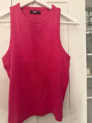 Rosa ribbad linnetopp från BikBok - Snygg rosa ribbad linnetopp från BikBok i storlek XL. Toppen är ärmlös med rund halsringning och har en croppad passform som passar perfekt till jeans eller kjol. Materialet är mjukt och stretchigt för extra komfort.
